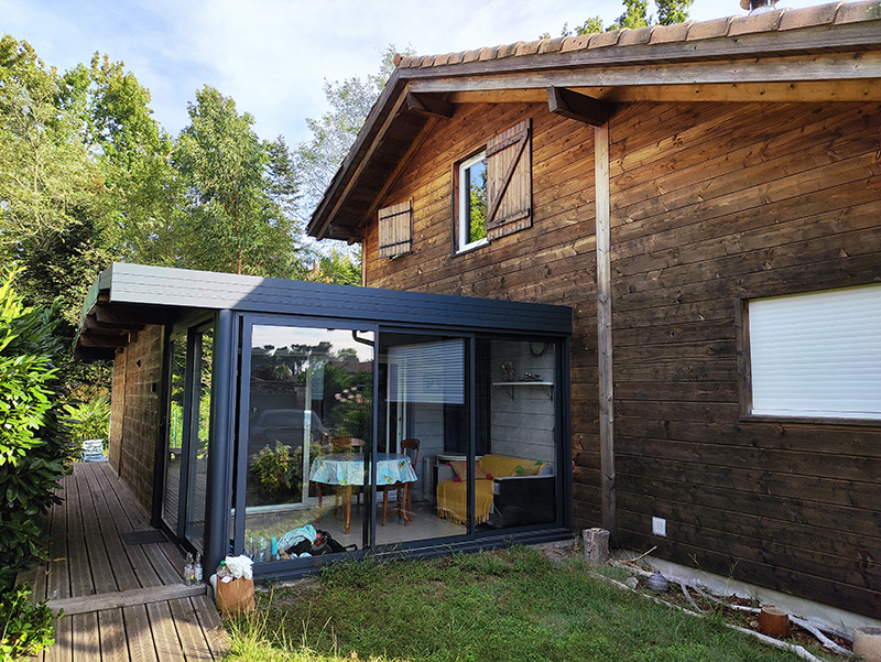 Photographie 1 de la maison en bardage bois avec sa véranda qui a servie de modèle à la réalisation du dessin personnalisé.